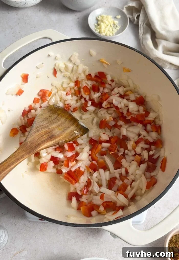 Hearty Butternut Squash Black Bean Chili 4 Diced onion and red bell pepper cooking gently in a large pot, forming the aromatic base for the chili.