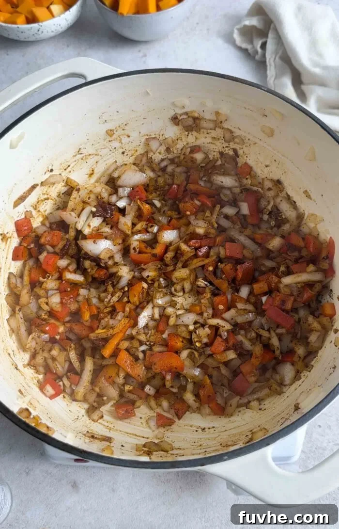 Hearty Butternut Squash Black Bean Chili 5 Diced onion, bell pepper, and garlic mixed with a vibrant blend of chili powder, cumin, and cinnamon in a pot, releasing their fragrant aromas.