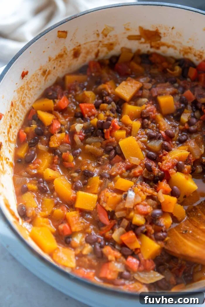 Hearty Butternut Squash Black Bean Chili 7 A large pot of hearty butternut squash chili with black beans simmering on the stovetop, developing deep flavors.
