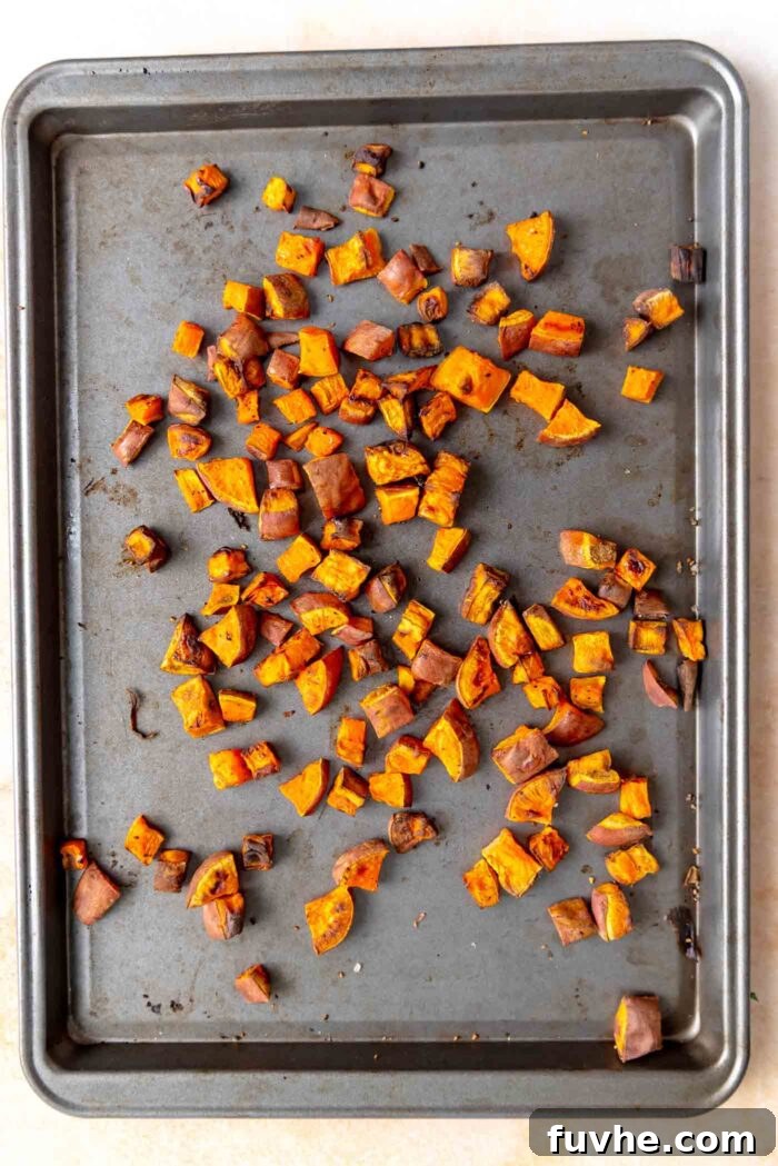 Small, evenly-sized cubes of sweet potato spread on a baking tray, ready for roasting to achieve perfect caramelization.