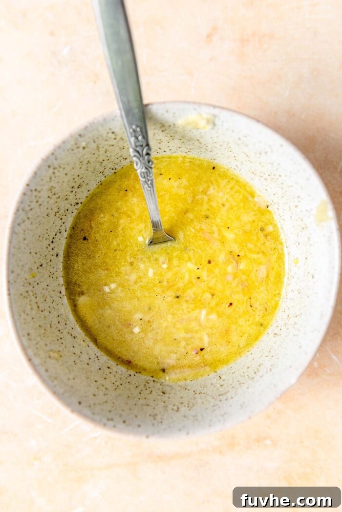 Vibrant Kale Quinoa Medley 5 A small, elegant dish filled with the freshly prepared, zesty lemon dressing, accompanied by a spoon for serving.