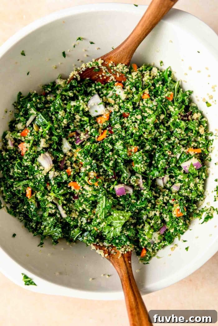Vibrant Kale Quinoa Medley 6 A large mixing bowl brimming with the colorful components of kale and quinoa salad, featuring vibrant carrots, red onion, and sweet cranberries, ready for dressing.
