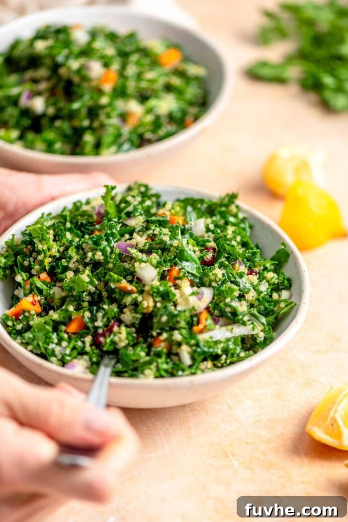 Vibrant Kale Quinoa Medley 7 A close-up shot of hands using a fork to enjoy a hearty bowl of kale quinoa salad, with blurred lemon wedges in the background.