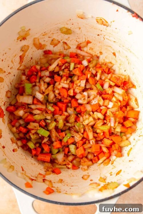 Celery, onion, carrot, garlic and spices cooking in a large pot.