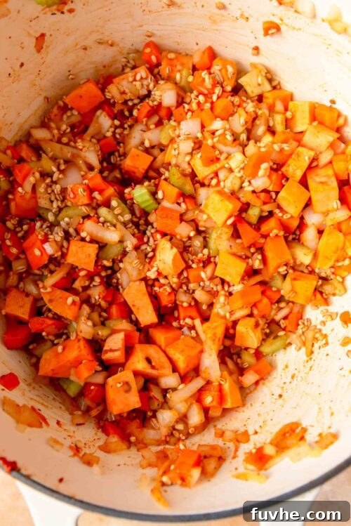Sweet potato, barley, celery, onion and carrot cooking in a large pot.