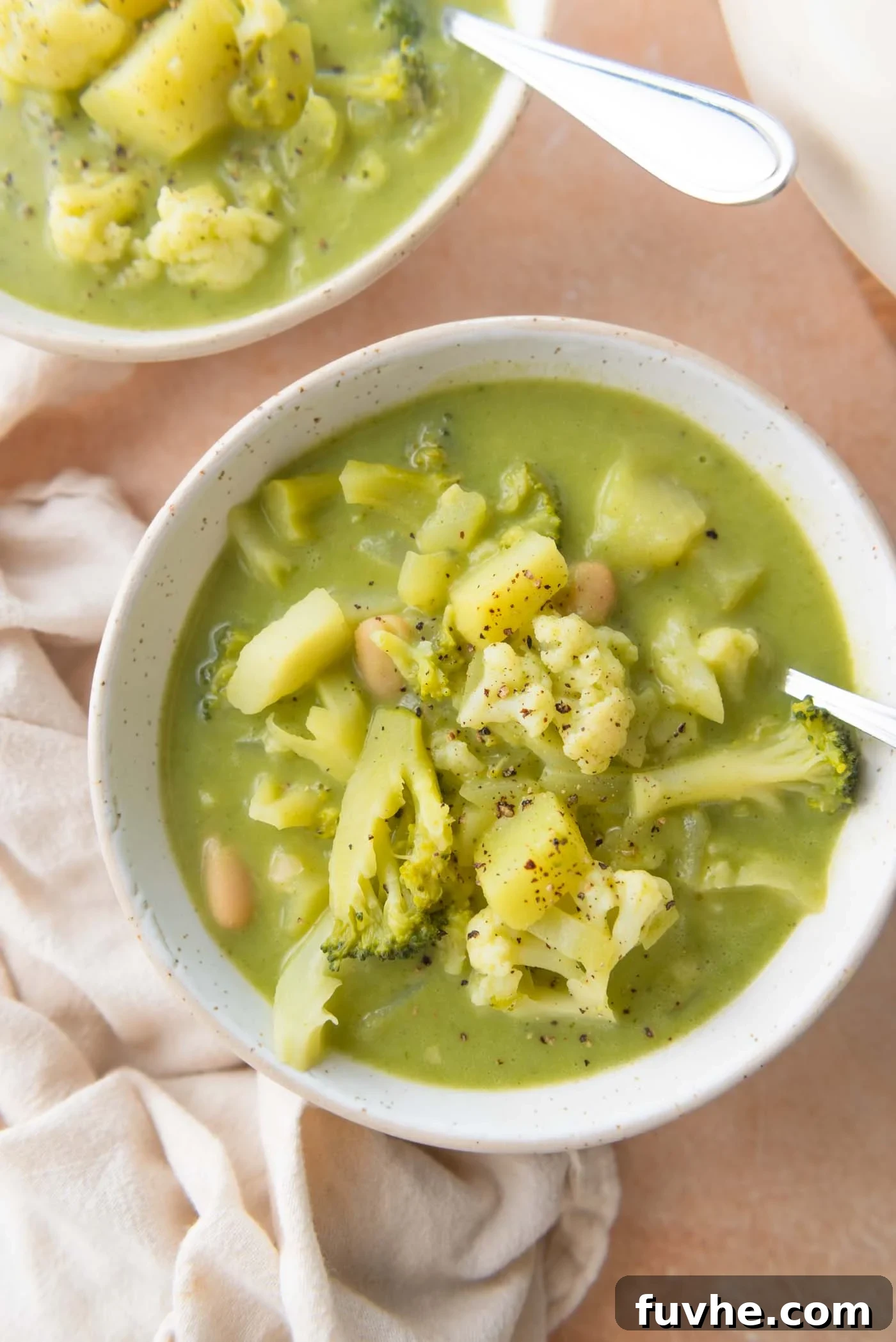 Velvety Vegan Broccoli & Cauliflower Bliss 2 A beautifully presented bowl of creamy vegan broccoli cauliflower soup, garnished with fresh herbs and served with crusty bread.