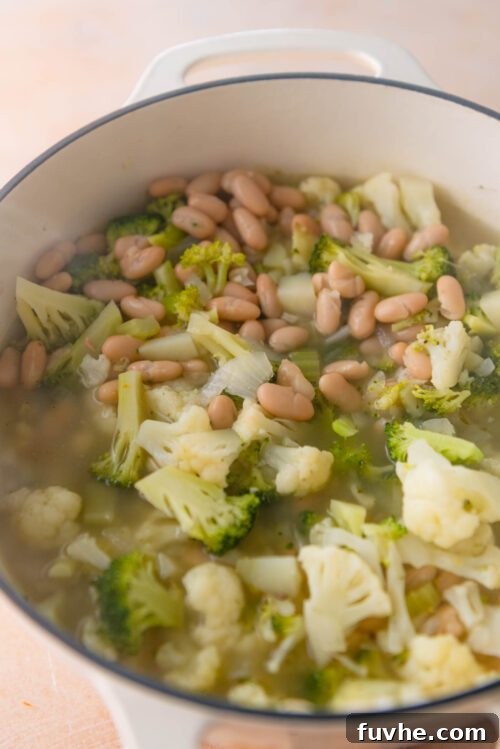 Velvety Vegan Broccoli & Cauliflower Bliss 6 The pot simmering with vegetable broth, broccoli, cauliflower, and potatoes, before the white beans are added.
