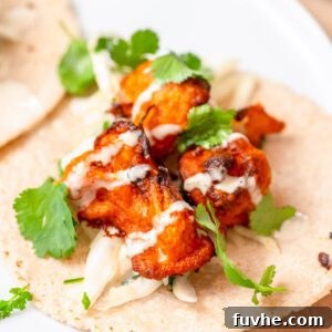 Pieces of buffalo cauliflower on a tortilla topped with cilantro and ranch sauce.
