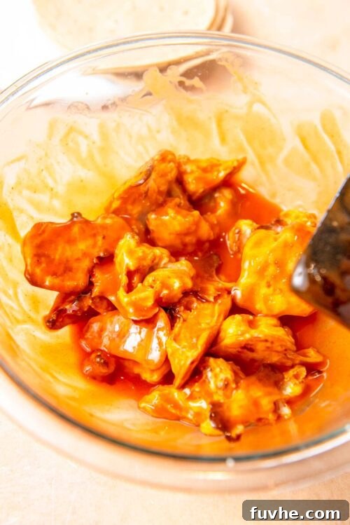 Crispy Buffalo Cauliflower Tacos 6 Roasted cauliflower florets generously coated in spicy buffalo sauce within a glass mixing bowl.