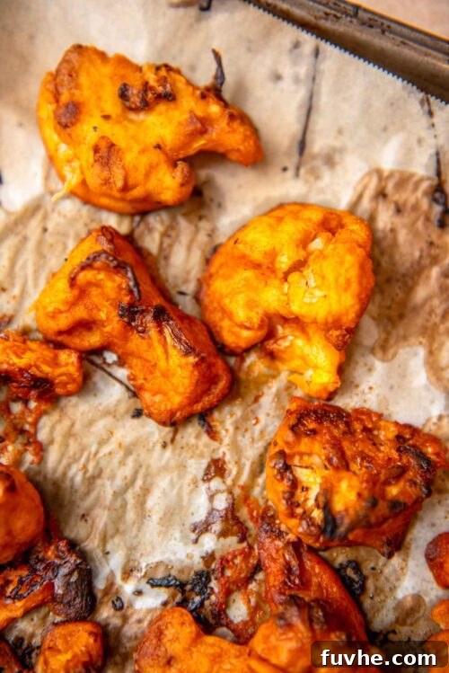 Crispy Buffalo Cauliflower Tacos 7 Baked buffalo cauliflower florets, golden and crispy, spread on a baking sheet.