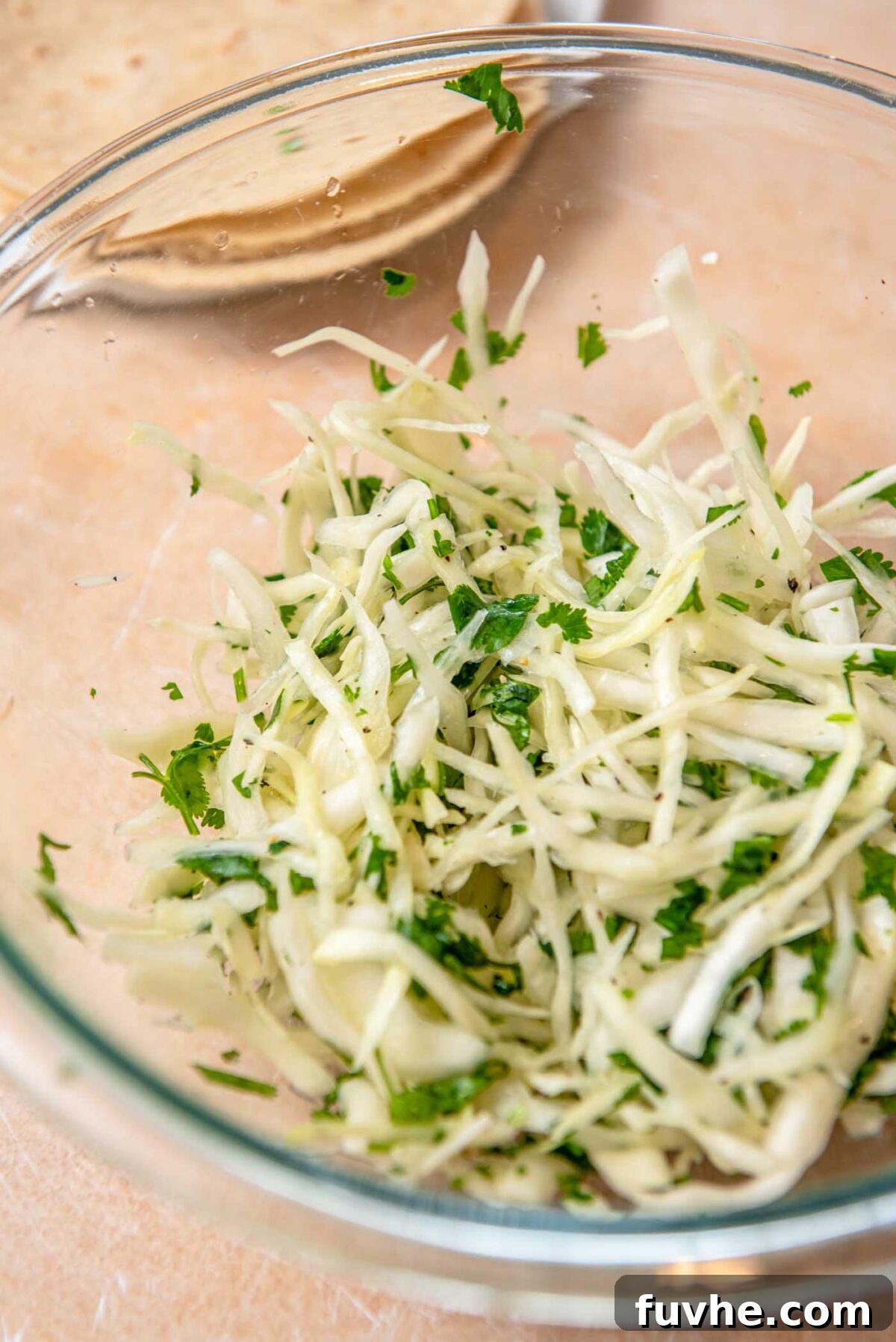 Crispy Buffalo Cauliflower Tacos 9 Shredded cabbage, fresh onion and cilantro in a glass bowl.