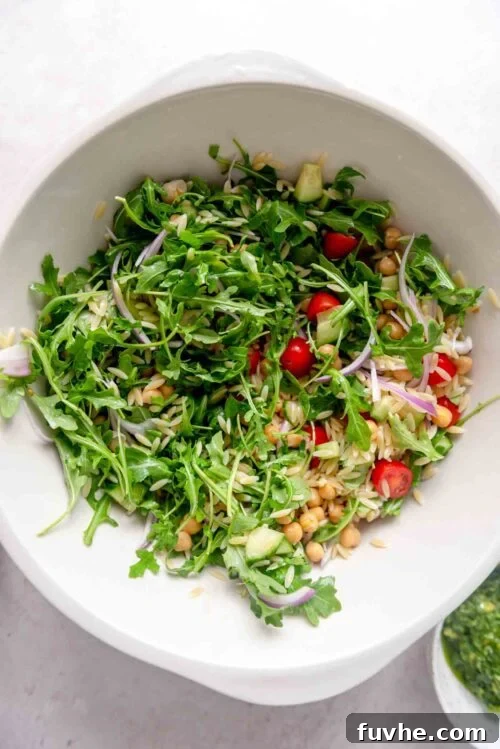 Bright Pesto Orzo Salad 5 Orzo pesto salad with tomatoes and chickpeas in a large mixing bowl.