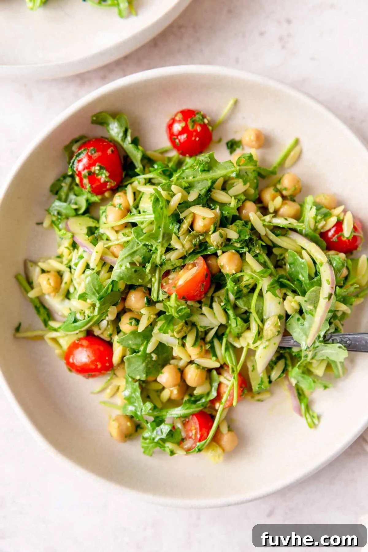 Bright Pesto Orzo Salad 7 Plate or orzo pesto pasta with chickpeas, tomato, red onion and arugula.