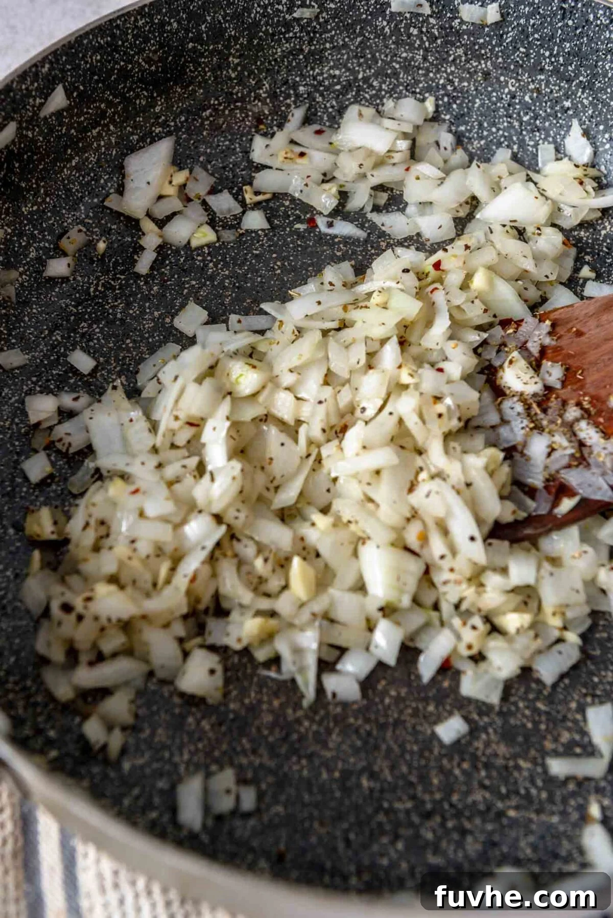 Diced onion, garlic and dried herbs cooking in a pan.