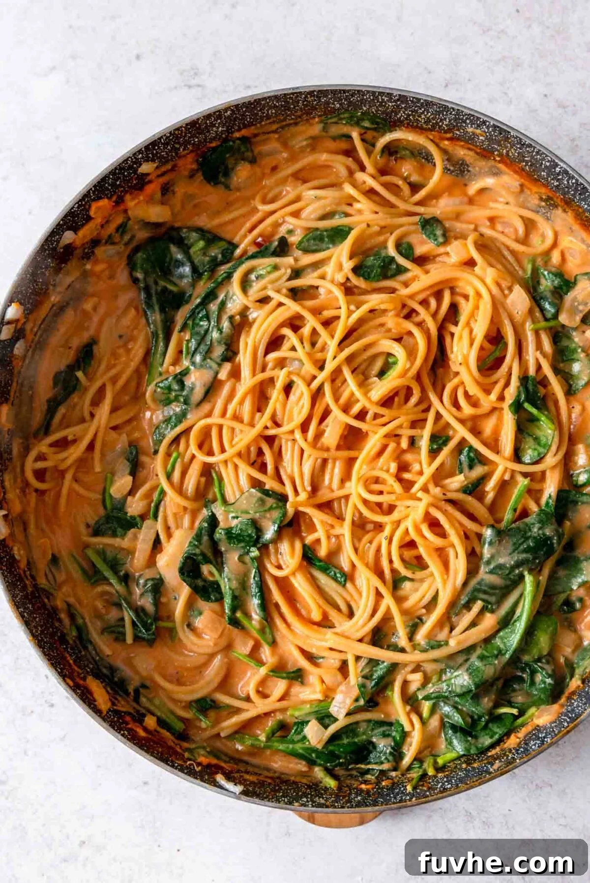 Large skillet of creamy tomato spaghetti with spinach.