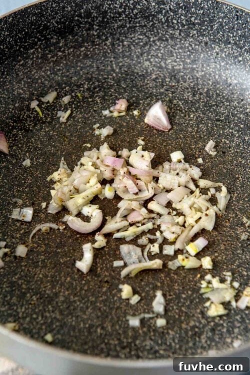 Minced garlic and shallot cooking in a large pan.