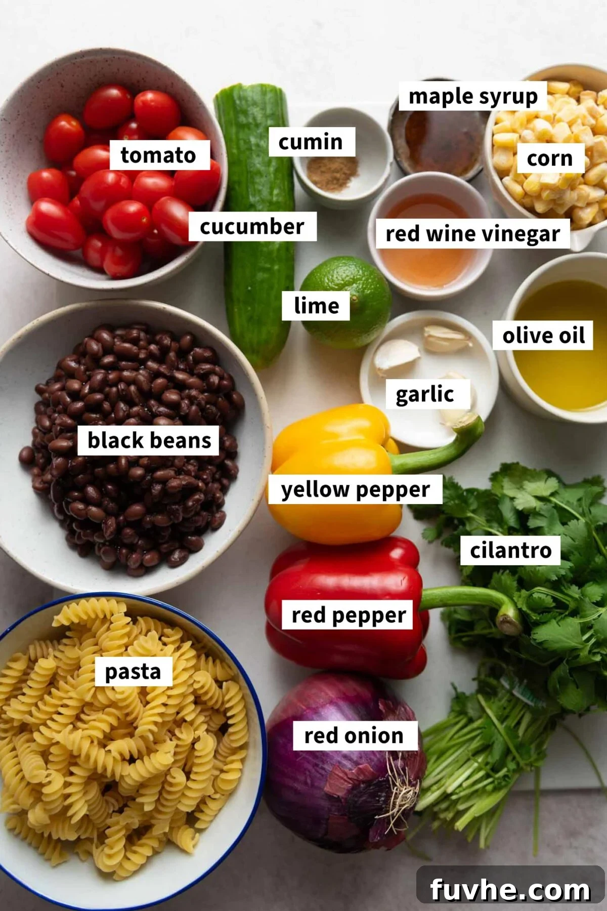 All the fresh and pantry ingredients neatly arranged for making a black bean corn pasta salad with tomato and cucumber.