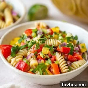 Bowl of vegan black bean pasta salad with tomatoes, cucumber, cilantro and corn.