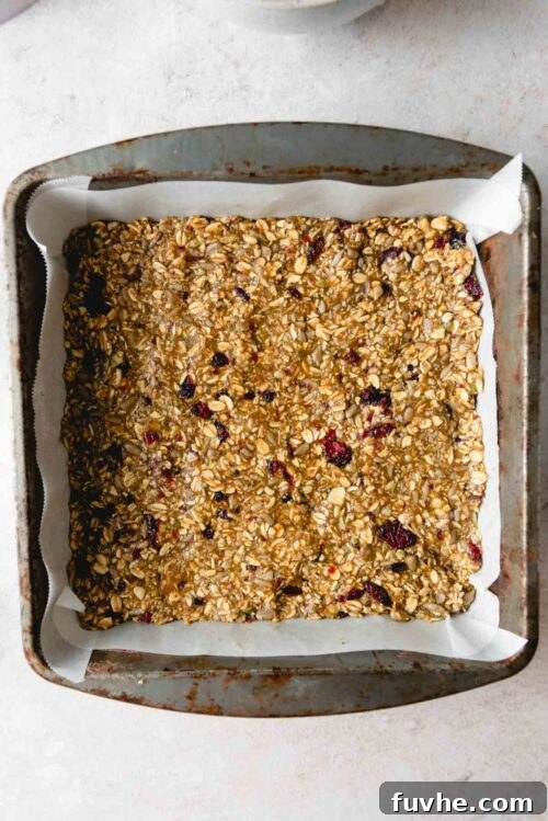Wholesome Cranberry Granola Bars 6 The dense cranberry granola bar mixture spread evenly and firmly pressed into a square baking pan, ready for its oven transformation.
