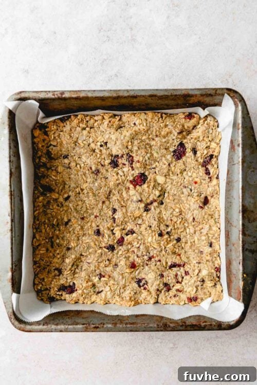 Wholesome Cranberry Granola Bars 7 A square metal baking pan filled with freshly baked cranberry granola bars, showcasing their beautiful golden-brown top and slightly crisp edges.