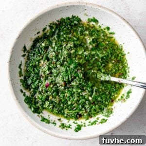 Vibrant green chimichurri sauce in a bowl with a spoon.