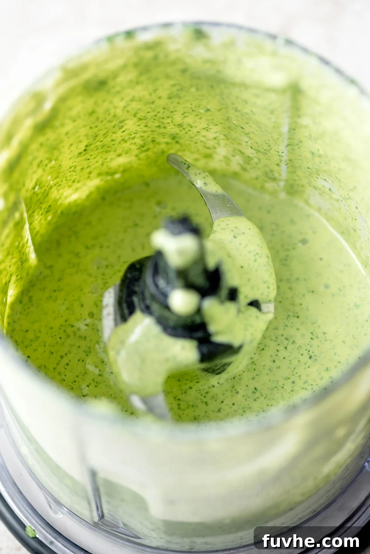 Green tahini sauce in a small blender.