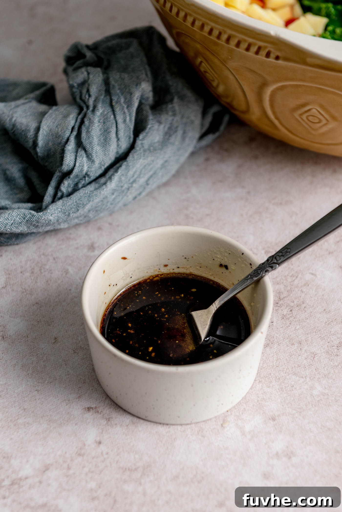 A small, elegant dish filled with freshly prepared homemade balsamic dressing, showcasing its rich color and smooth texture.