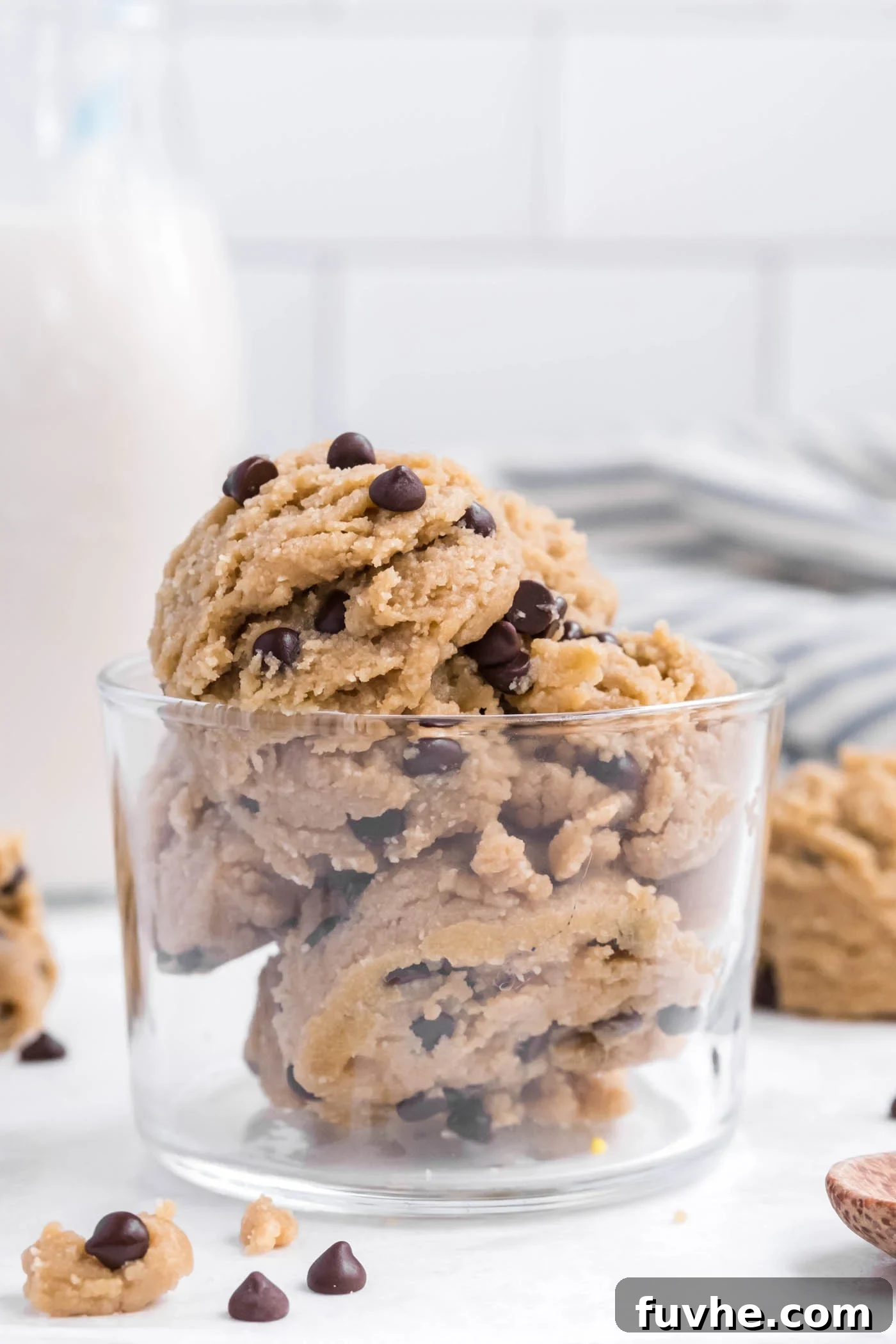 A small glass bowl overflowing with scoops of rich, edible chocolate chip cookie dough.