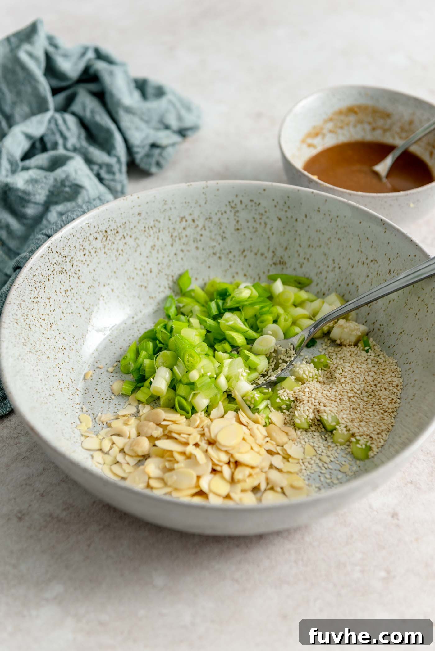 Almonds, green onions and sesame seeds in a bowl.