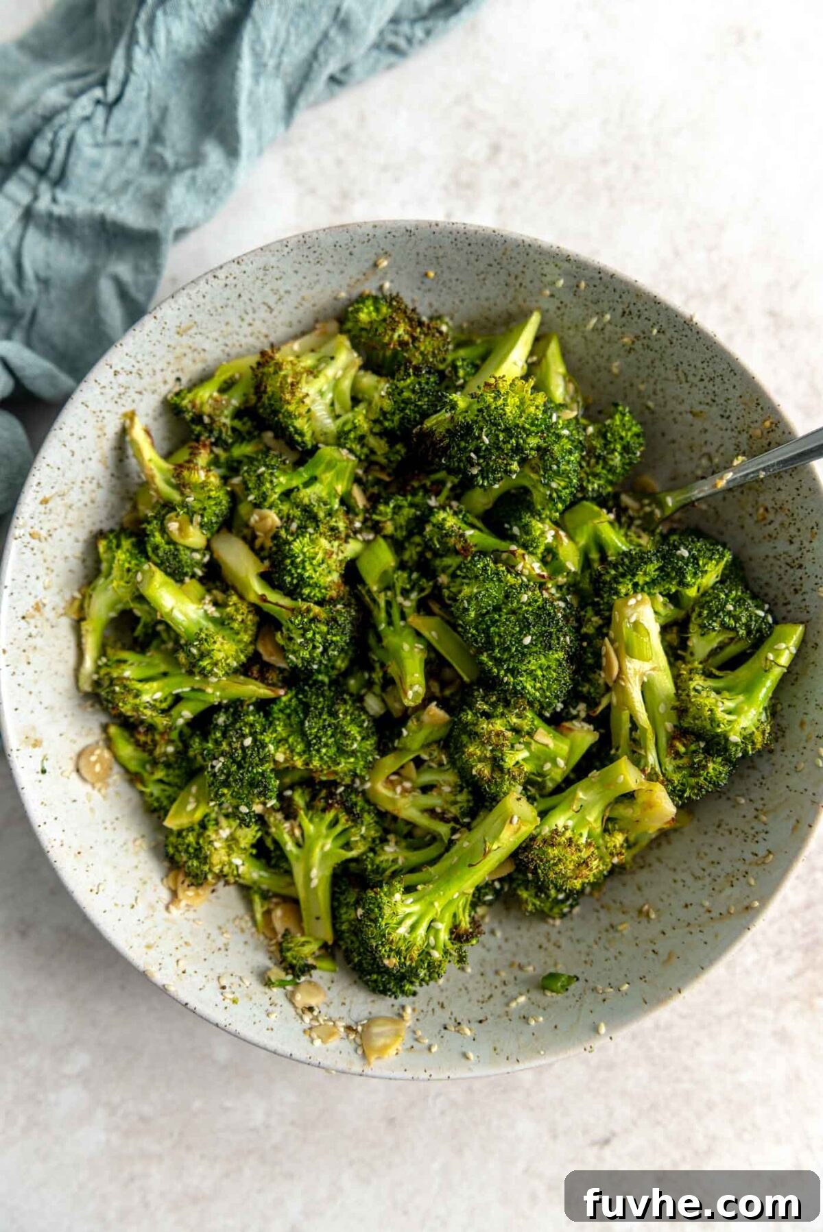 Roasted broccoli with almonds, sesame seeds and green onions in a bowl.