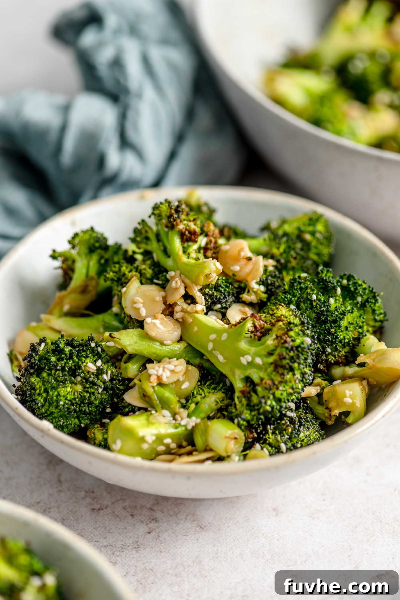 Bowl of roasted broccoli salad with slivered almonds and green onions.