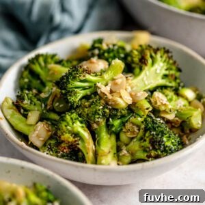 Bowl of roasted broccoli salad with slivered almonds and green onions.