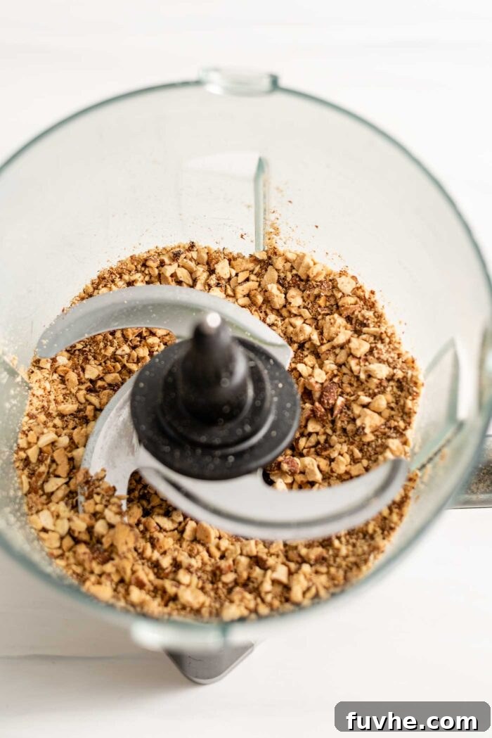 Tropical Coconut Fuel Bars 3 Raw almonds being processed into a grainy flour in a food processor.