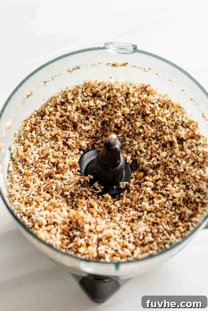 Tropical Coconut Fuel Bars 4 Dates, coconut, and hemp seeds blended with processed almonds in a food processor, forming a crumbly, doughy mixture.