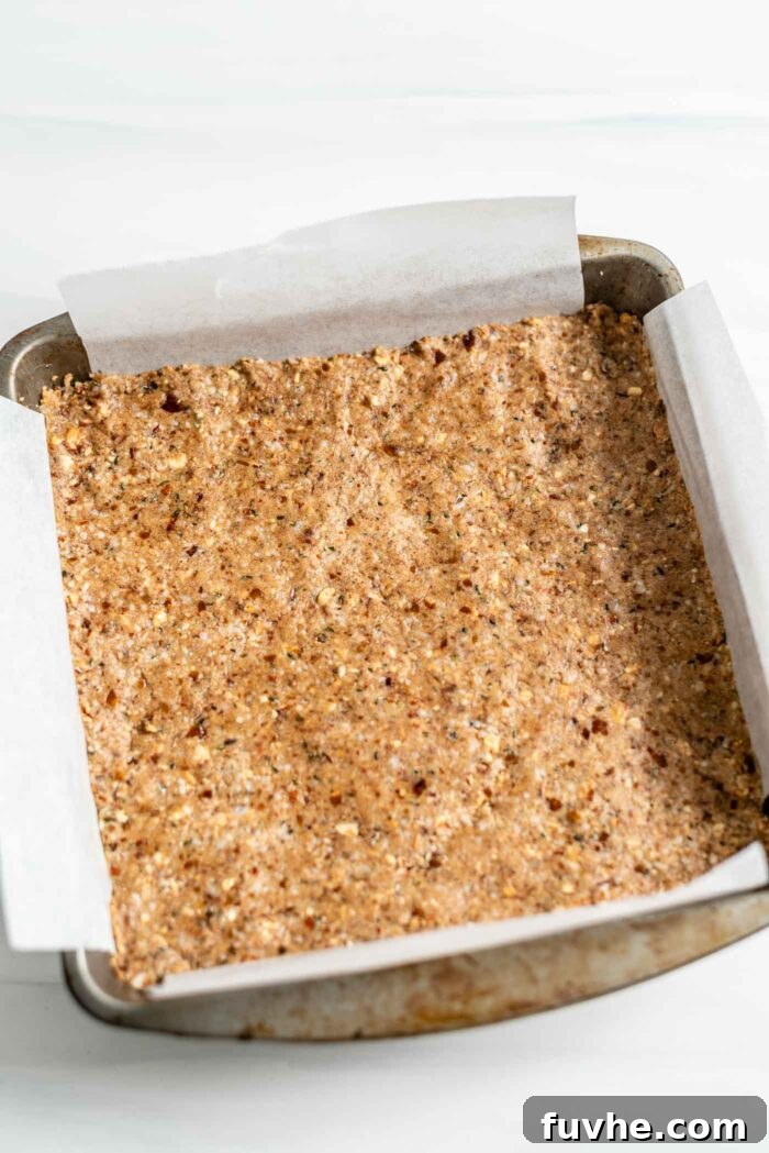 Tropical Coconut Fuel Bars 6 A parchment paper-lined metal baking pan with the firmly pressed protein bar dough, ready for chilling.