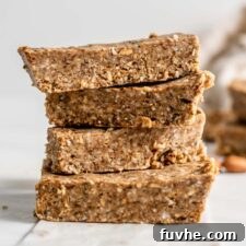A stack of 4 energy bars with a few almonds scattered around them.