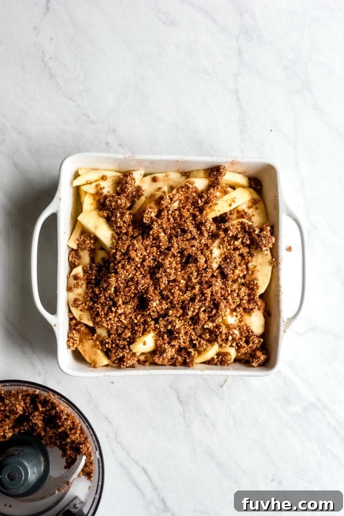 Date and almond crust over chopped and peeled apples in a baking dish.