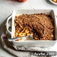 Grain-free vegan apple crisp being scooped out of a white baking dish.