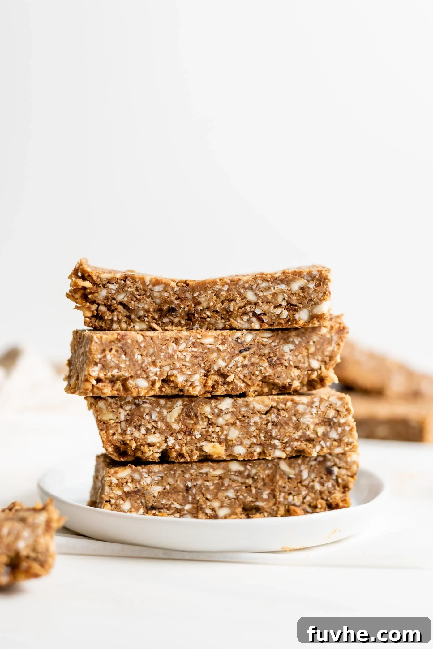 Stack of 4 energy bars on a small plate. More bars in foreground and background.