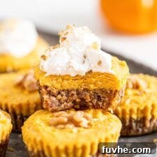 Front view of a pumpkin pie tart with a bit taken of it to show inside. Whipped cream on top.