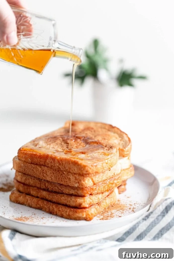 Tropical Coconut Vegan French Toast 2 A stack of golden-brown coconut vegan french toast being generously topped with flowing maple syrup.