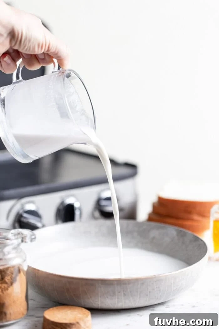 Tropical Coconut Vegan French Toast 4 Pouring a container of creamy coconut milk into a mixing bowl to start the batter.