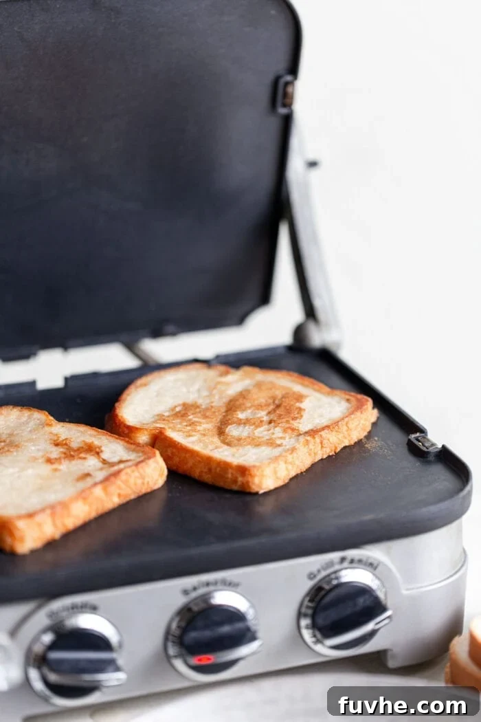 Tropical Coconut Vegan French Toast 6 Two slices of golden-brown vegan French toast cooking on a hot griddle, emitting steam.
