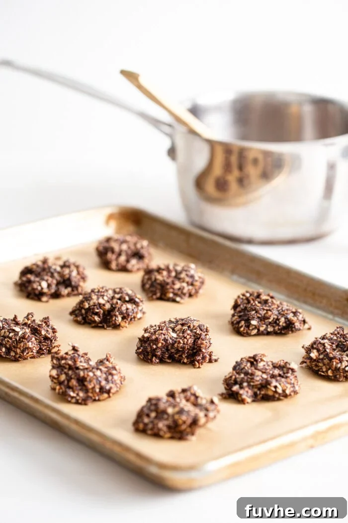 Freshly dropped no-bake gingerbread oatmeal cookies arranged on a baking sheet lined with parchment paper, awaiting chilling.