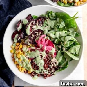 A perfectly portioned vegan wild rice bowl, showcasing the vibrant colors of roasted beets, golden corn, and hearty chickpeas, all topped with a creamy herb lemon yogurt sauce, captured beautifully from above.