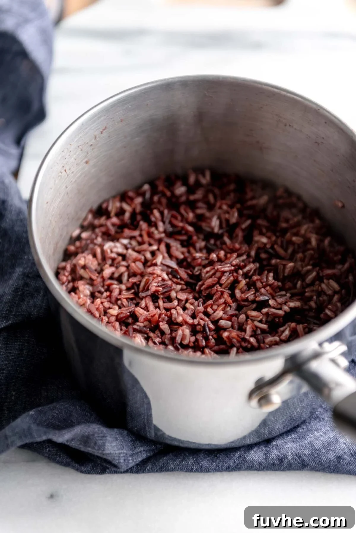 Perfectly cooked wild rice nestled in a pot, resting on a clean marble cutting board, ready to be incorporated into delicious and healthy bowls.