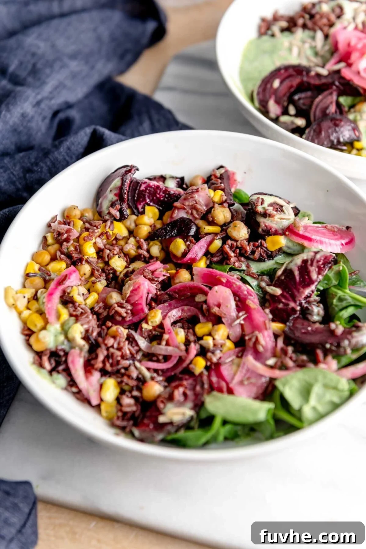 A vibrant wild rice salad, artfully arranged with tangy pickled onion, sweet corn, and hearty chickpeas, served in a rustic bowl on a marble cutting board, capturing the essence of a wholesome and delicious plant-based meal.