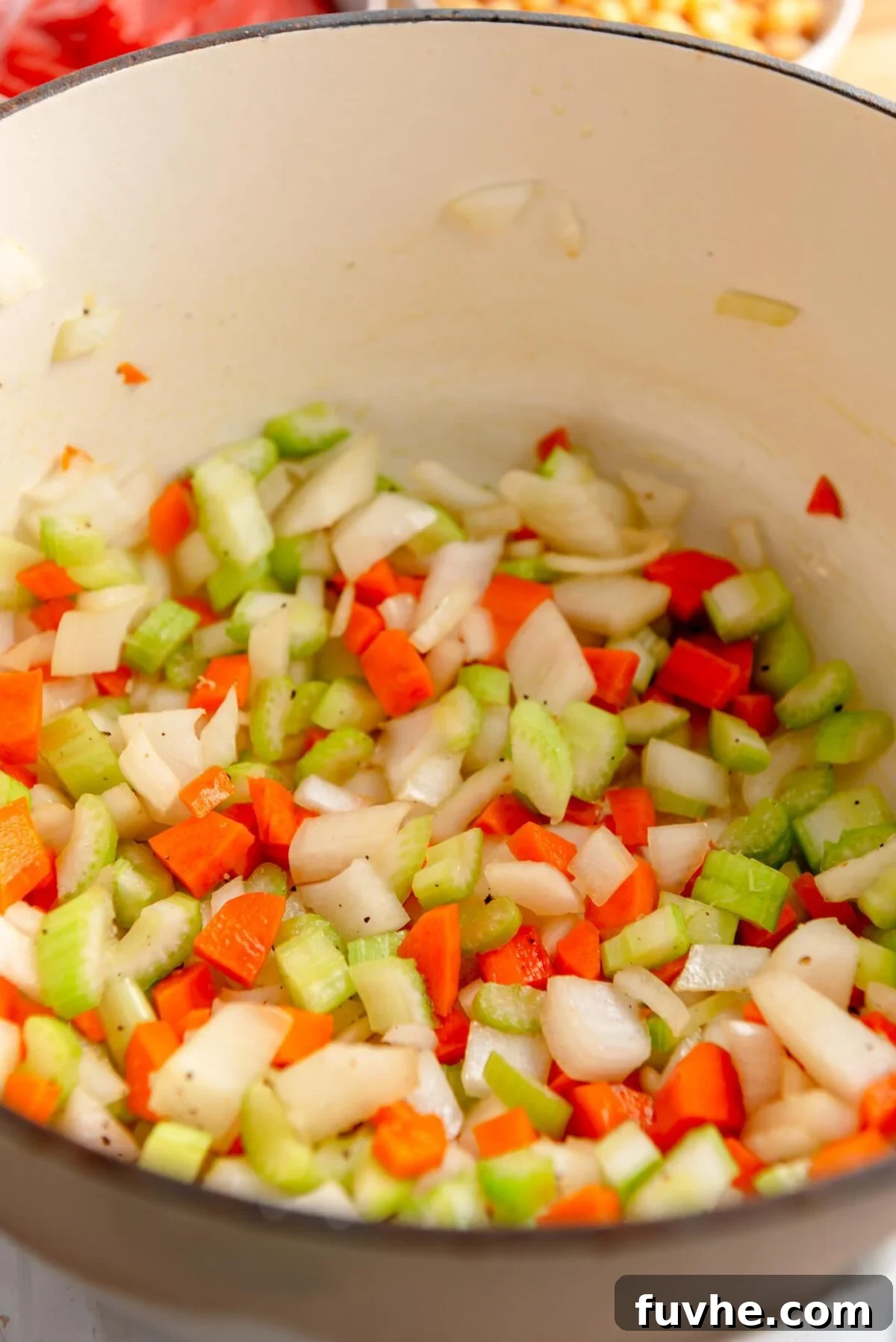 Vibrant Tomato Orzo Soup 4 Diced carrots, onion, and celery gently cooking in olive oil in a large soup pot, forming the aromatic base for the soup.