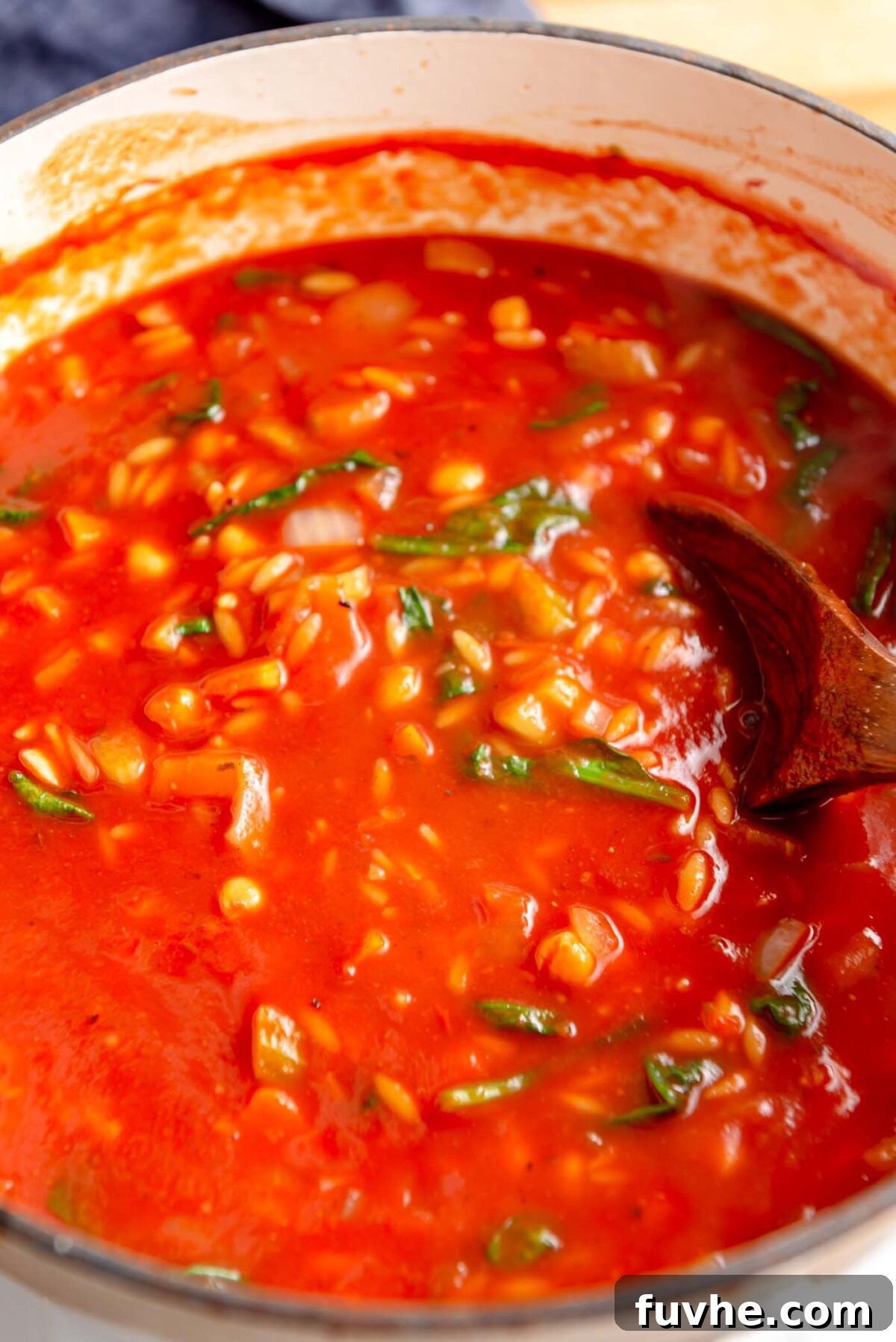 Vibrant Tomato Orzo Soup 8 Fresh spinach being stirred into a comforting pot of tomato orzo soup with chickpeas, wilting beautifully into the broth.