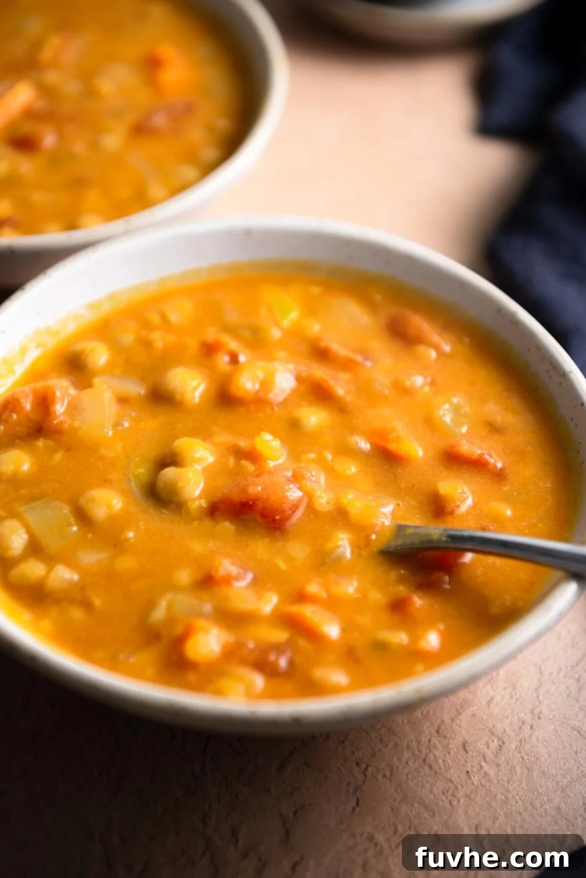 Bowl of creamy lentil chickpea soup with a spoon in it.